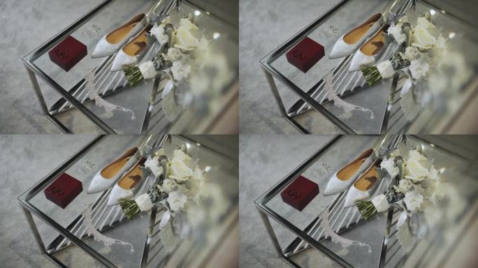 新娘的白鞋，结婚戒指和新娘的珠宝放在酒店房间的玻璃桌上，慢镜头。