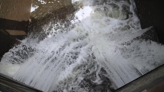 暴风雨般的水流从水闸的木门流出，俯视图。