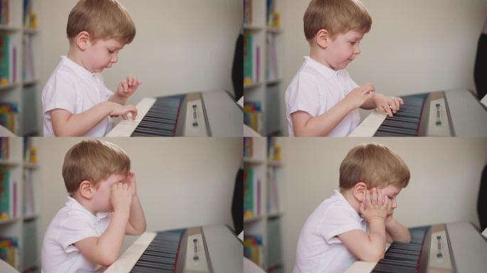 小男孩把胳膊肘放在钢琴键盘上，靠在手上