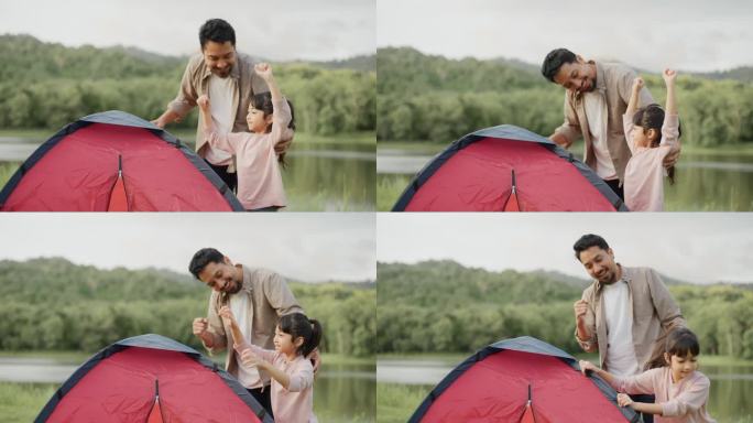 亚洲小女孩帮助她的父母在公园的河边搭起一个帐篷。