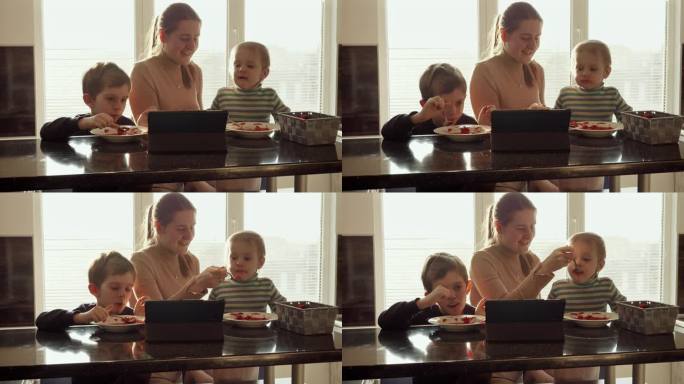 两个可爱的男孩一边喝汤一边看平板电脑视频。家常菜，在家做饭，孩子健康营养