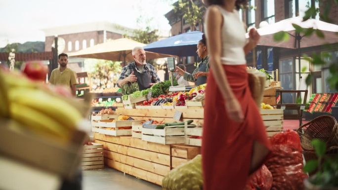多民族小企业主在户外农贸市场出售精选的生态水果和蔬菜。逛广场的顾客，购买新鲜的有机农产品