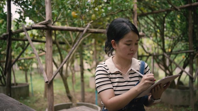 一位农场女工用她的数字平板电脑检查她的植物，并检查花园里作物的信息。
