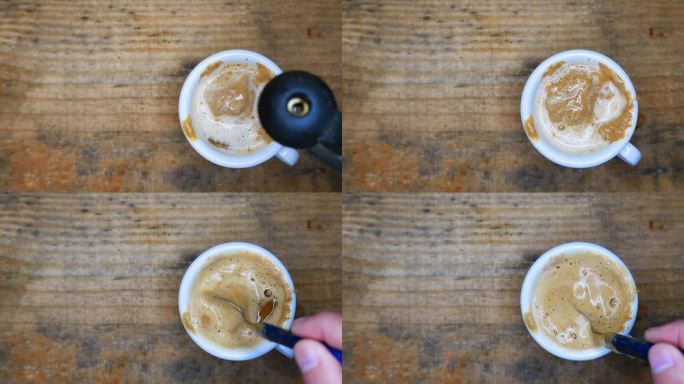 一杯美丽的奶油咖啡:将沸水倒在一杯奶油咖啡上。用勺子搅拌咖啡。桌上有一杯咖啡。表格，俯视图。热气从热