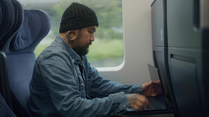 亚洲人，自由职业者，在铁路运输途中用笔记本电脑工作。