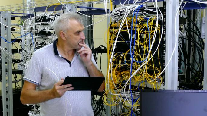 系统管理员带着平板电脑在服务器机房工作