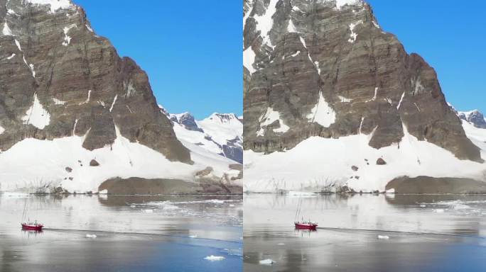 垂直视频:一艘船在南极洲雄伟的雪山附近航行。