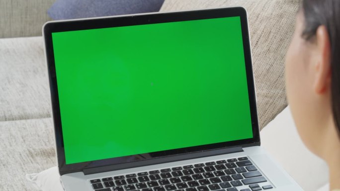 一位匿名女性在舒适的家中工作，使用带有绿屏模拟显示的笔记本电脑无缝管理任务和项目