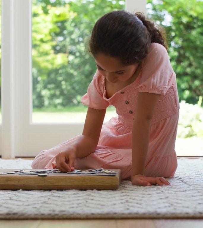 垂直视频的女孩在家里坐在地板上在休息室做拼图游戏