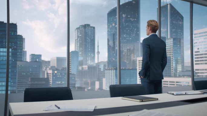 白人首席执行官走进他的角落办公室，拥有大城市的视野。男性企业家站在窗前，若有所思地看着窗外，计划商业