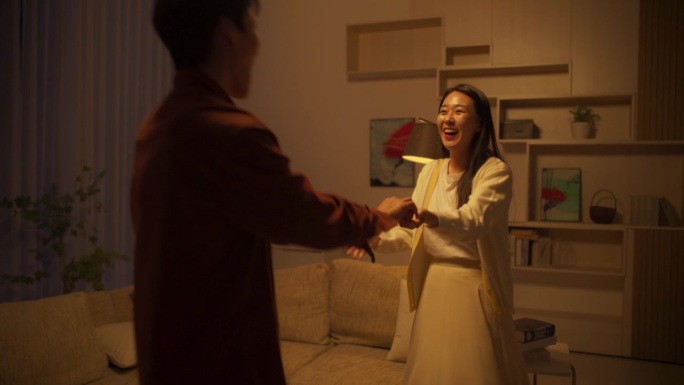 美丽的韩国夫妇在客厅跳舞，享受在家的浪漫时光。男朋友和女朋友一起随着音乐起舞，为他们俩举办一个晚会