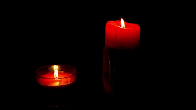 两支红烛在黑暗中燃烧，火在风中摇曳，