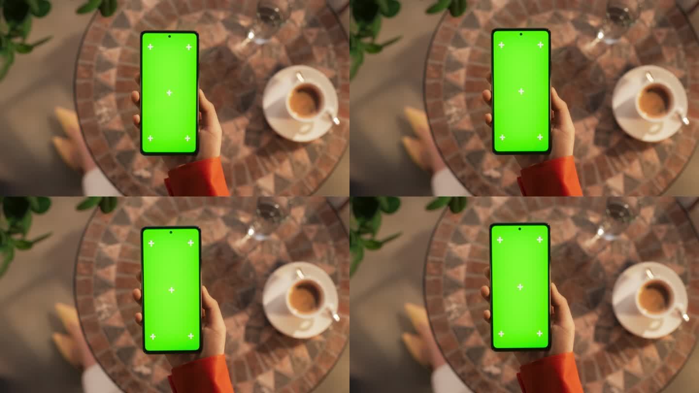 一个女人坐在咖啡桌旁，拿着智能手机，看着一个绿色的Chromakey模拟显示屏。视频模板与占位符的数