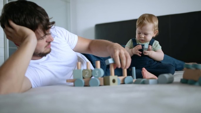 父亲和他的儿子一起用玩具积木制作木制火车。