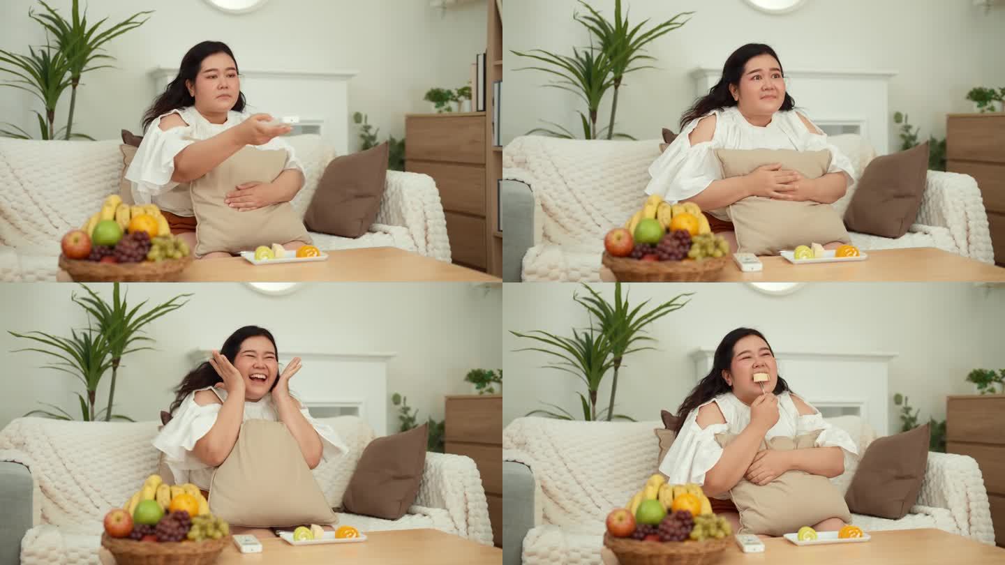 一个肥胖的亚洲年轻女子坐在沙发上，拿着遥控器换频道，看一部爱情剧。