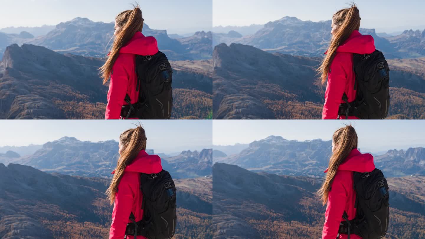 女人站在山顶上，欣赏周围群山的壮丽景色