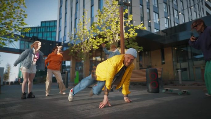 年轻健壮的B-Boy在朋友圈的现代建筑之间的城市街道上跳霹雳舞。时尚的年轻人支持舞者，用智能手机拍摄