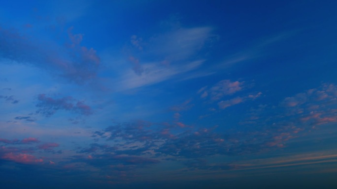 不同深浅的云。日落时的白色卷云向不同方向移动。间隔拍摄。