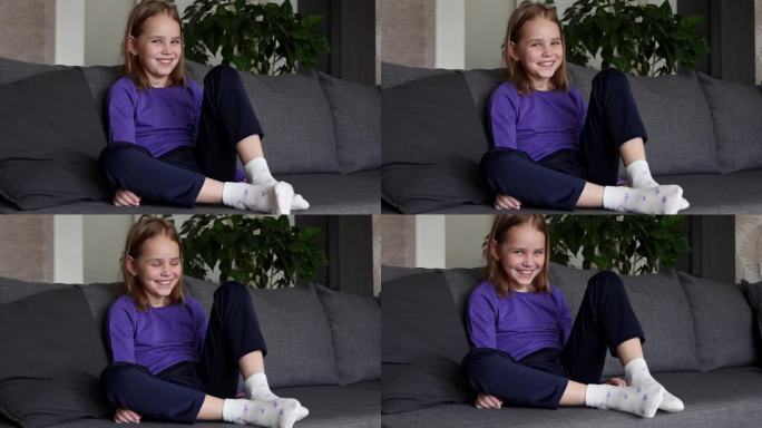 一个可爱的金发小女孩把带星星的白袜子穿在脚上。孩子的独立性。低龄学童着装技巧的发展。
