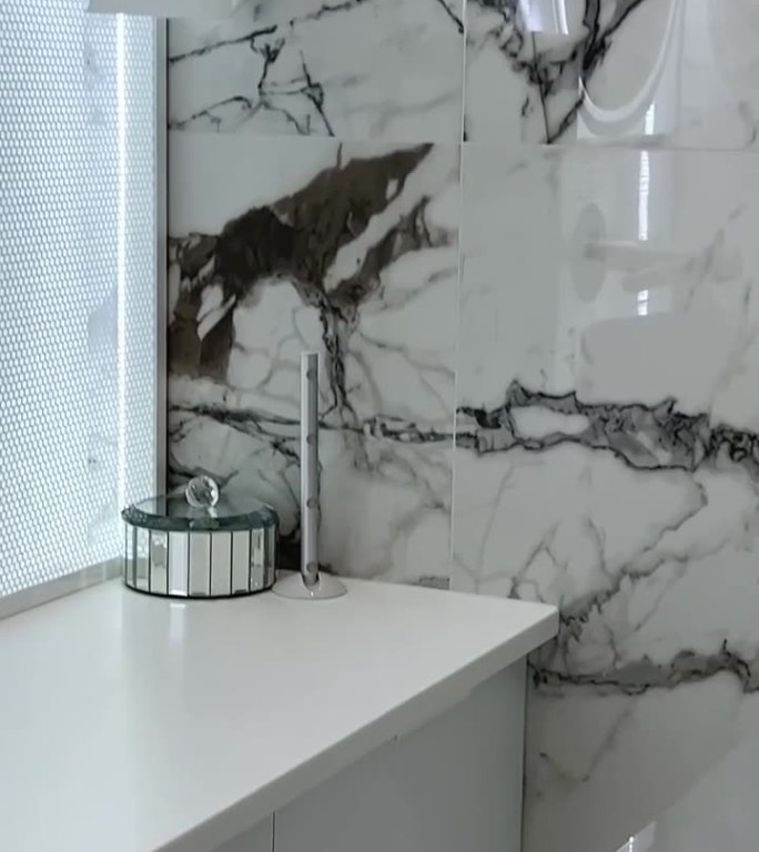 卫生间的特写坐在浴室上淋浴间的隔断玻璃闪亮的白色浴室门打开，你可以看到一堵灰色的墙