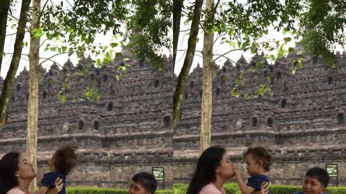 一位亚洲妇女和她的儿子坐在草地上，背景是婆罗浮屠寺