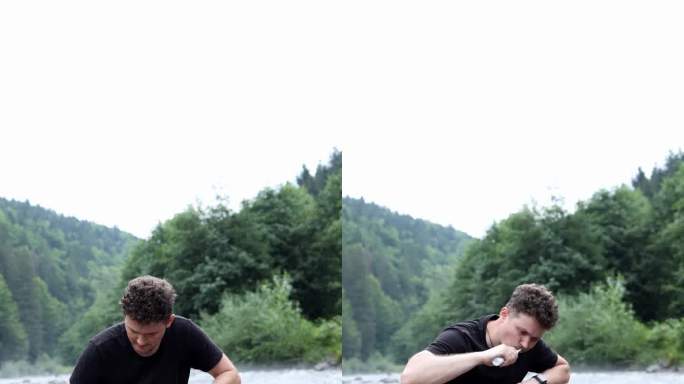 一个男孩游客坐在山上河边的石头上，用电子牙刷刷牙。在山上洗澡。垂直视频