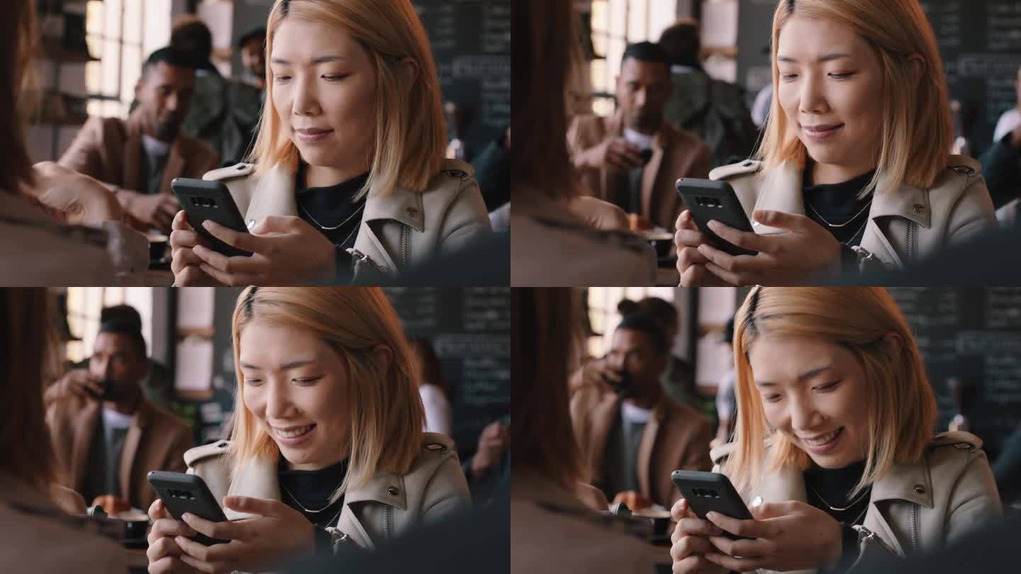 美丽的亚洲女人在咖啡馆用智能手机发短信，在社交媒体上分享信息，享受移动技术，在繁忙的餐厅等待