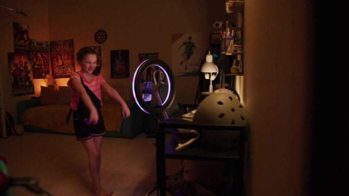 男子在卧室里弹电吉他。镜头转向拍摄舞蹈视频的年轻女孩。