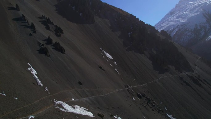 空中鸟瞰四名徒步旅行者在喜马拉雅山脉的蒂里科大本营徒步旅行。徒步探险，游客在导游的带领下安全地在尼泊