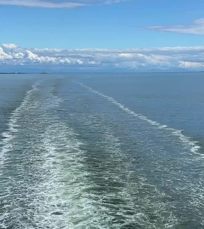 一艘巨大的班轮，一艘游轮，你可以看到沸腾的水，美丽的天空，周围的海洋，这艘船正在驶离加拿大到温哥华岛