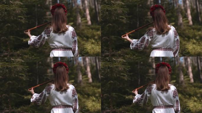 年轻女子演奏木管木笛-乌克兰特伦卡或泰林卡在森林背景。民间音乐概念。乐器。身穿传统刺绣衬衫的音乐家。