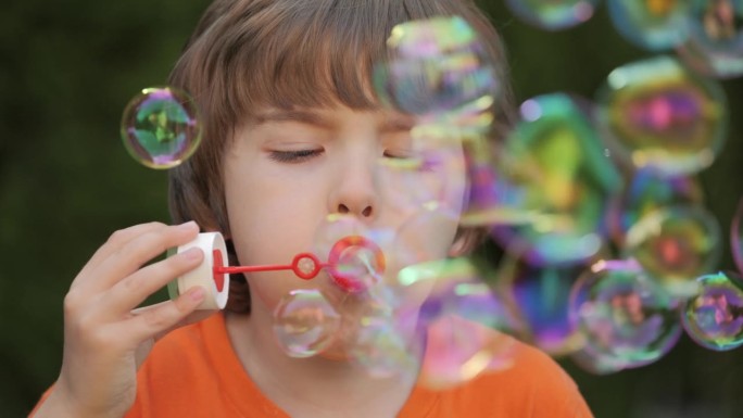 吹肥皂泡的小男孩在外面玩得很开心，孩子的天真和好奇心。在公园、花园和大自然中吹泡泡，享受快乐、快乐和