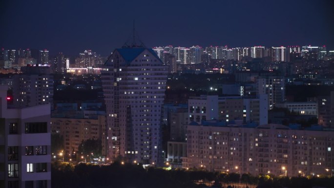 现代多层住宅上空的深蓝色夜空。高架景观城市天际线。夜间灯光照明延时。背景夜间延时。城市夜景