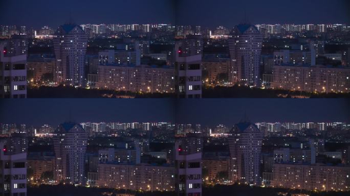 现代多层住宅上空的深蓝色夜空。高架景观城市天际线。夜间灯光照明延时。背景夜间延时。城市夜景