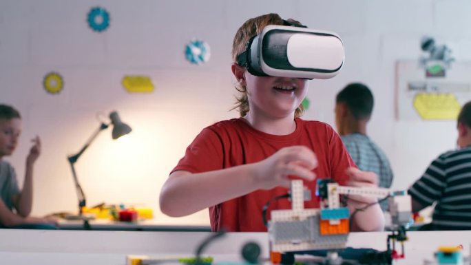 虚拟现实，虚拟世界和教育与一个男孩在机器人课堂上学习或儿童发展。技术，互动和界面与学生使用虚拟现实耳