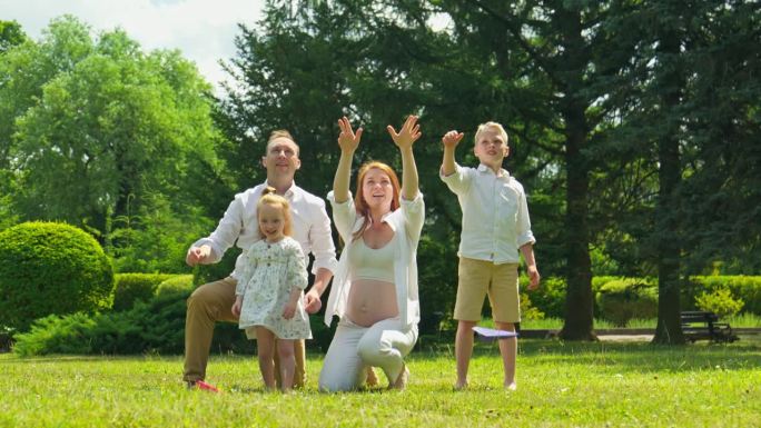 一家人在公园里玩纸飞机。父母和孩子玩得开心