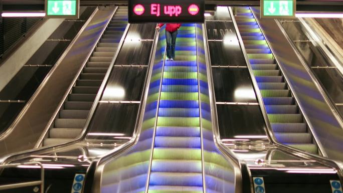 成熟女性在地铁站搭乘自动扶梯往下走
