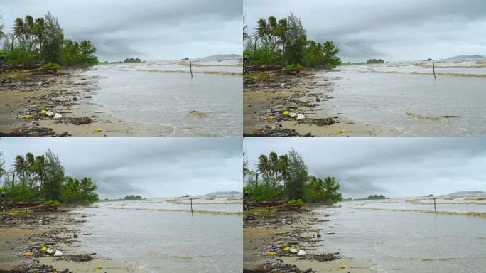 汹涌的海浪带着浑浊的海水和沙滩上的垃圾来到海滩上，同时暴雨。