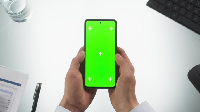 匿名人士使用智能手机模拟绿屏Chromakey显示与占位符。男子双手垂直拿着手机，在手机上滑动和敲击