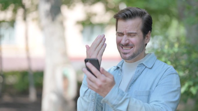 沮丧的美国男子被智能手机震惊的户外照片