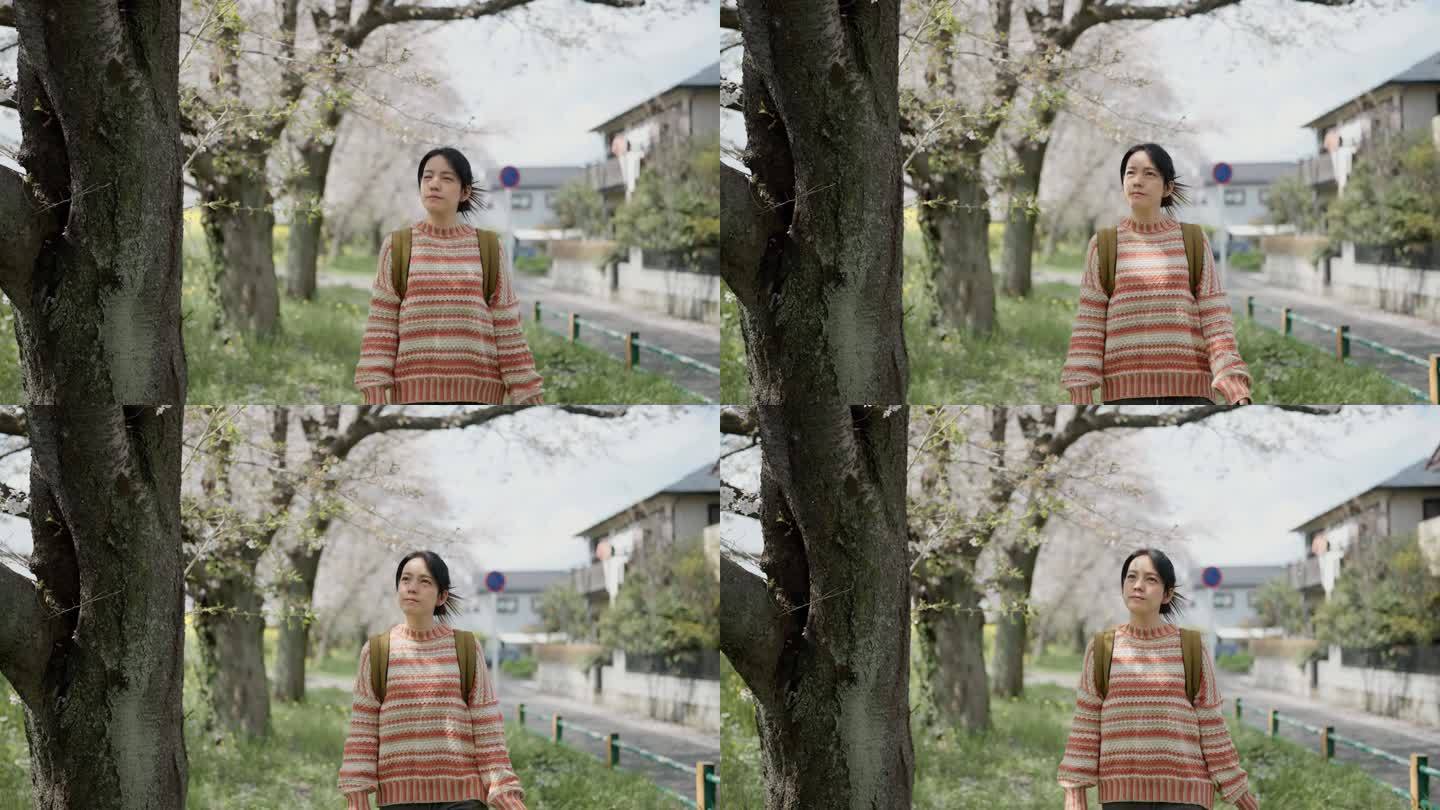一位亚洲妇女走在黄色的田野里，背景是樱花。在旅途中感到放松和精神焕发。
