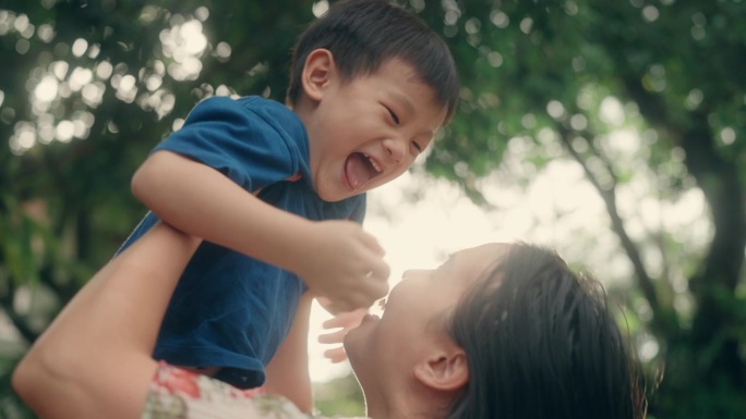 在家的幸福:慈爱的亚洲妈妈把兴奋的儿子扔到前院的空中。