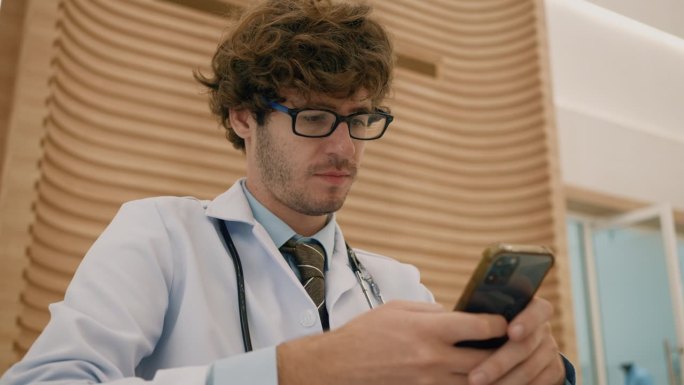 在现代医院工作的医生手持和使用数字智能手机。一名外科医生坐在诊所里浏览网上研究技术。一个人在查他的日