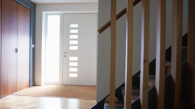 现代住宅中带有楼梯和前门的明亮明亮的走廊