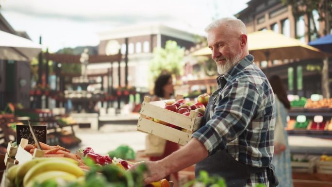 中年男性农民在户外农贸市场经营小生意，销售可持续有机水果和生态蔬菜。老人在大排档上摆熟苹果