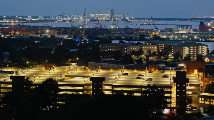 带停车场的城市屋顶:建筑屋顶在夜间有了照明的停车场，变得活跃起来。远处的海运码头，朴茨茅斯，弗吉尼亚