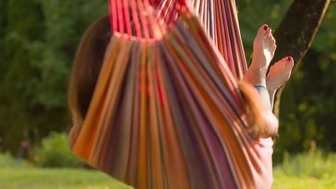 Woman swaying and daydreaming in a hammock in back