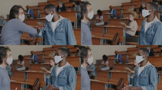 大流行期间，戴口罩的年轻男学生在大学课堂上用手肘打招呼、交谈