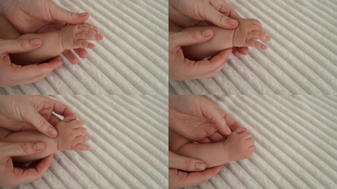 特写镜头，无法辨认的妈妈在家里舒适的床上按摩宝宝的手臂、手掌和手指。小儿推拿护理女医生。