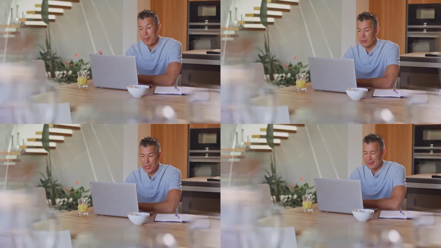 一个在家工作的人坐在餐桌旁开视频会议